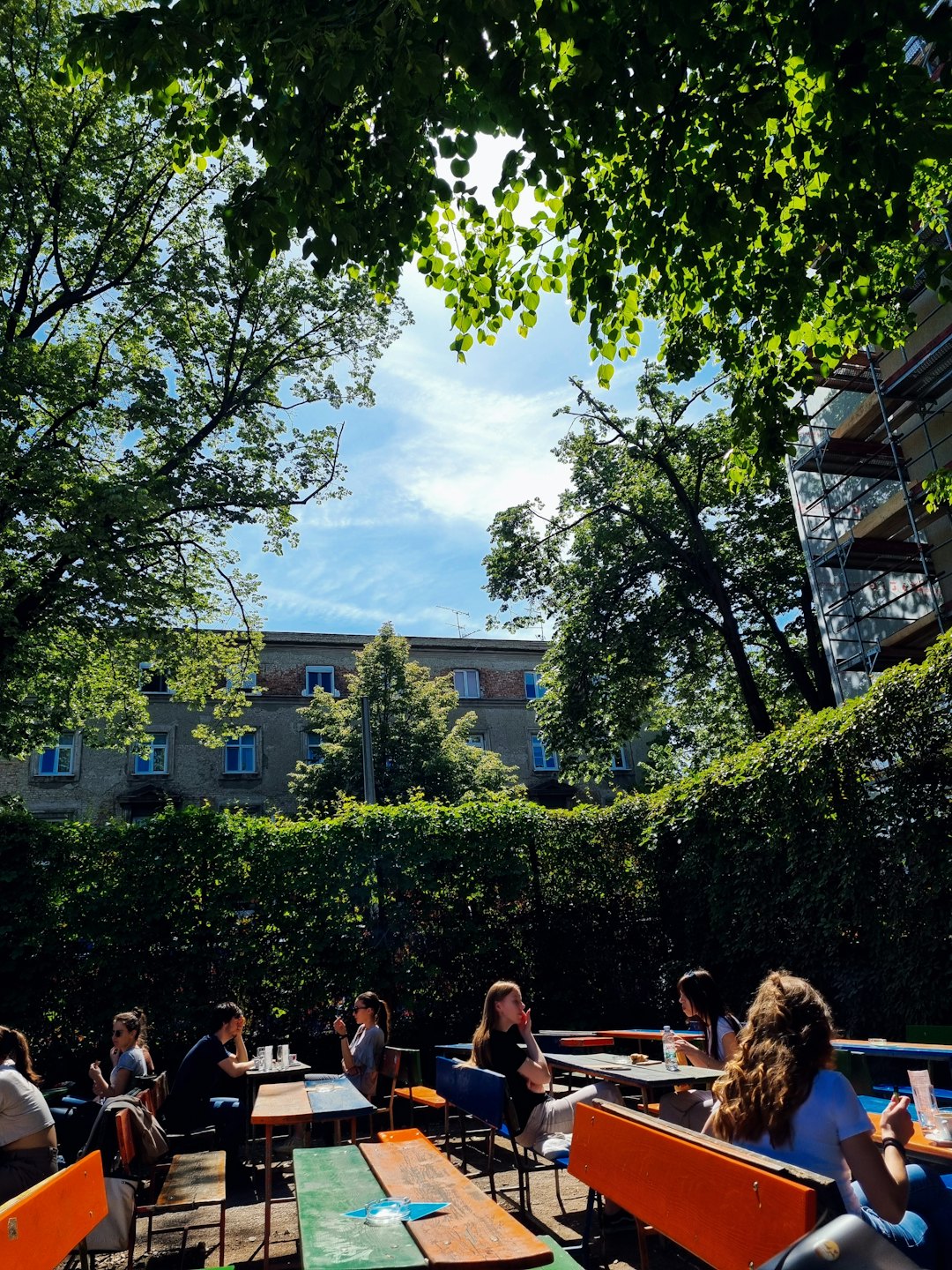 Young adults chatting at outdoor cafe tables on a sunny day.